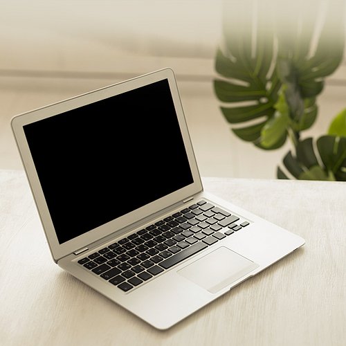 Aufgeklapptes Laptop auf Tischplatte, schwarzer Bildschirm